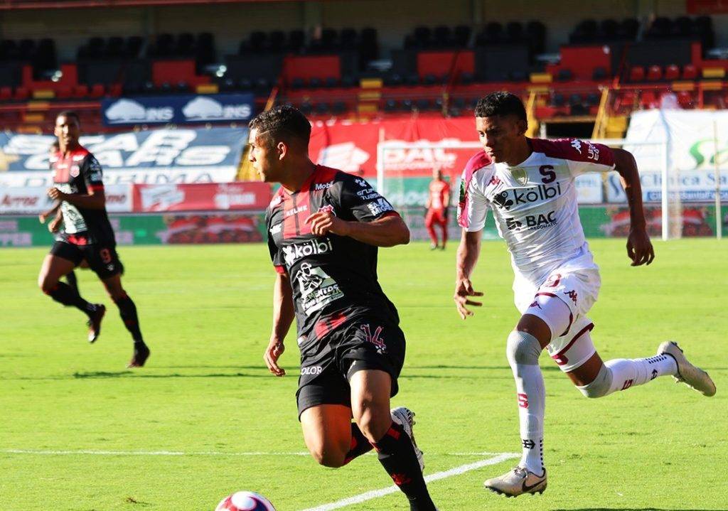 Jugador de Alajuelense, geancarlo Castro, se lleva el balón por delante de Jordy Evans, lateral de Saprissa.